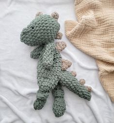 a crocheted stuffed animal laying on top of a bed next to a blanket