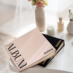 two books sitting on top of a table next to vases with flowers in them