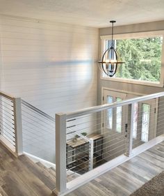 the inside of a house with white walls and wood flooring, stairs leading up to a second story window