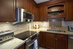 a kitchen with wooden cabinets and stainless steel appliances, including an oven, microwave, dishwasher, and sink