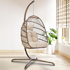 a hanging chair in the middle of a room with a potted plant on the far side