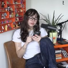 a woman sitting in a chair looking at her cell phone