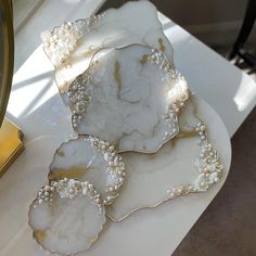 three white plates with pearls on them sitting on a table next to a mirror and clock