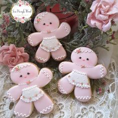 three decorated cookies sitting on top of a lace doily next to flowers and a potted plant