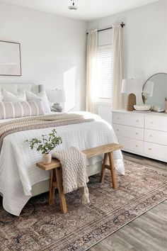 a bedroom with a large bed and white furniture