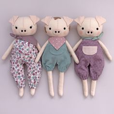 three stuffed animals are laying next to each other on a white surface and one is wearing overalls