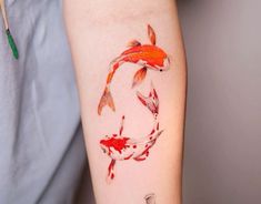 a person with a tattoo on their arm that has two koi fish in it