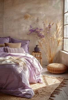 a bed with purple comforter and pillows in a room next to a large window