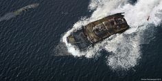 an aerial view of a boat in the middle of the ocean with two smaller boats behind it