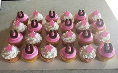 a table topped with lots of cupcakes covered in pink and brown frosting