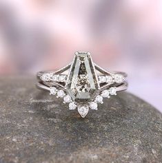 a diamond ring sitting on top of a rock with diamonds around it's edges