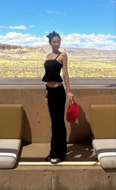 a woman standing on top of a cement bench next to a wall with mountains in the background