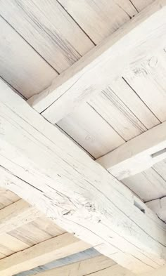 a clock on the side of a white wooden building with beams and wood flooring