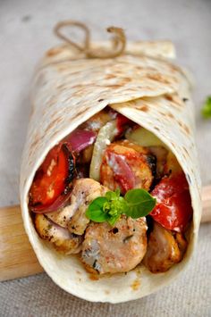 a wrap filled with meat and vegetables on top of a table