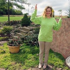 a woman standing in front of a stone wall with her hands up and one hand raised