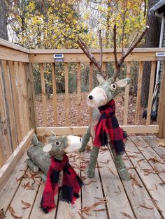 two stuffed animals sitting on top of a wooden deck next to each other in front of trees