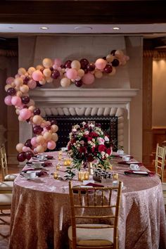 the table is set for a party with balloons and flowers in front of the fireplace