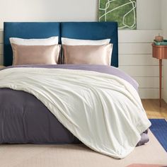 a bed with two pillows on top of it and a blue headboard in the background