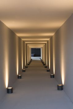 an empty hallway with several lights on either side and one light at the end that is lit up