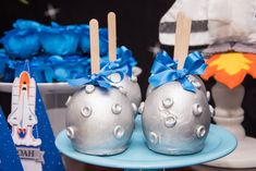 two silver cake pops sitting on top of a blue plate next to other dessert items