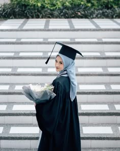 a woman in a graduation gown holding flowers