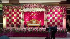 a man standing in front of a red and white stage set up for a wedding