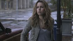 a woman standing next to a car in the rain