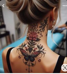 a woman's back neck tattoo with flowers and butterflies on the upper part of her neck