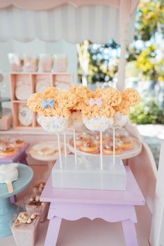 there are some cupcakes on the table in front of the dessert stand with flowers