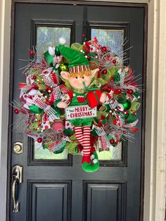 a christmas wreath on the front door of a house with an elf's hat