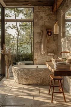 a bathroom with stone walls and flooring next to a large window that looks out onto the outdoors