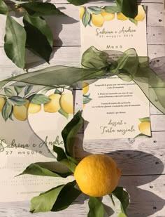 two lemons are sitting on the table next to some cards with leaves and ribbons