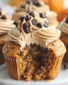 cupcakes with frosting and chocolate chips are on a white plate next to oranges