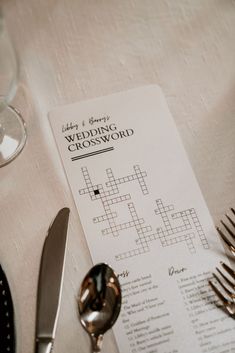 a crossword puzzle on a table next to silverware and wine glasses with forks