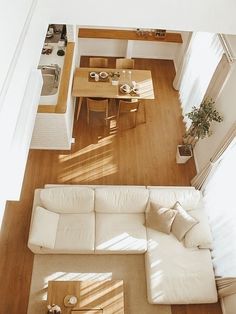 an overhead view of a living room and dining room with wood flooring, white couches and table