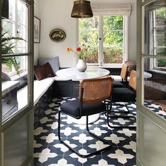 a dining room with black and white tile flooring next to a large open window