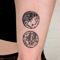 a woman's arm with two coin tattoos on the left side of her body