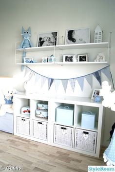 a baby's room is decorated in blue and white with pictures on the shelves