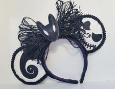 a black and white mickey mouse ears headband with skulls on the side, decorated with feathers