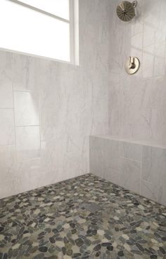 a bathroom with white walls and tile flooring next to a window in the shower