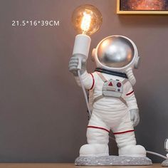 an astronaut holding a light bulb on top of a table