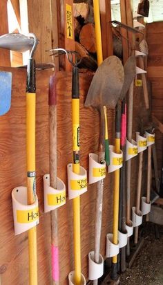 there are many different tools hanging on the wall in this shed, including shovels and rakes