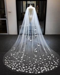 a wedding veil with white flowers on the bottom is displayed in front of a store