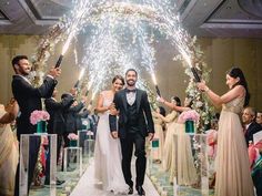 a newly married couple walking down the aisle with sparklers in their hands as guests look on