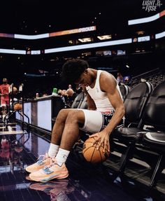 a man sitting on top of a basketball court with his foot in the air while holding a basketball