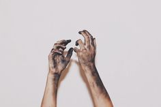 two hands that are covered in black and white paint, reaching up towards each other