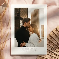 an image of a couple kissing in front of some gold fan blades on a pink blanket