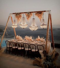 an outdoor dining table set up with chandeliers and flowers on the tables for dinner