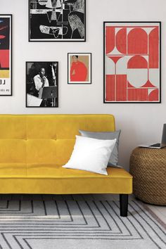 a yellow couch sitting in front of a wall with pictures on it's walls