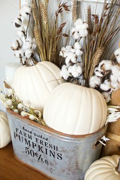 some white pumpkins and cotton in a metal container on a table with other autumn decorations